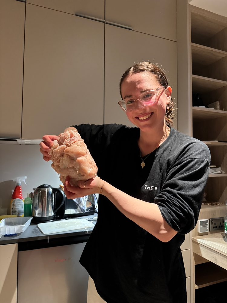 Christina smiling and holding a frozen block of chicken