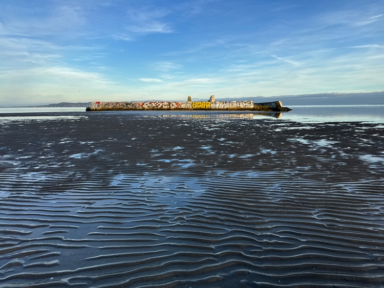 A concrete structure on a beach with wavy sand