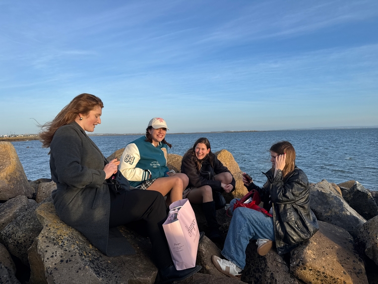 Pam, Christina, Lisanne, and Kadin talking on some rocks at the beach