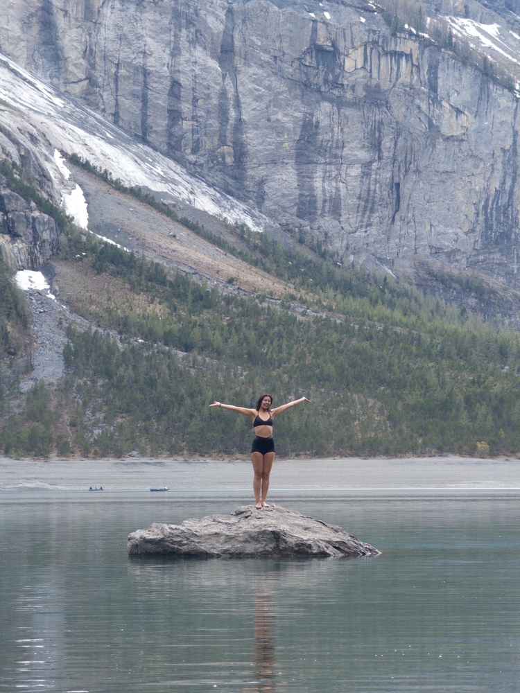 A victorious Kate standing on a rock in the middle of the lake