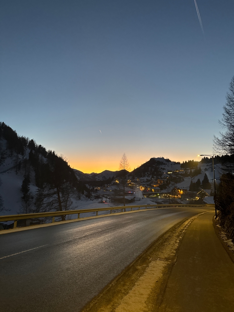 A beuatiful gradiented dusk cupped by mountains behind a long, winding road