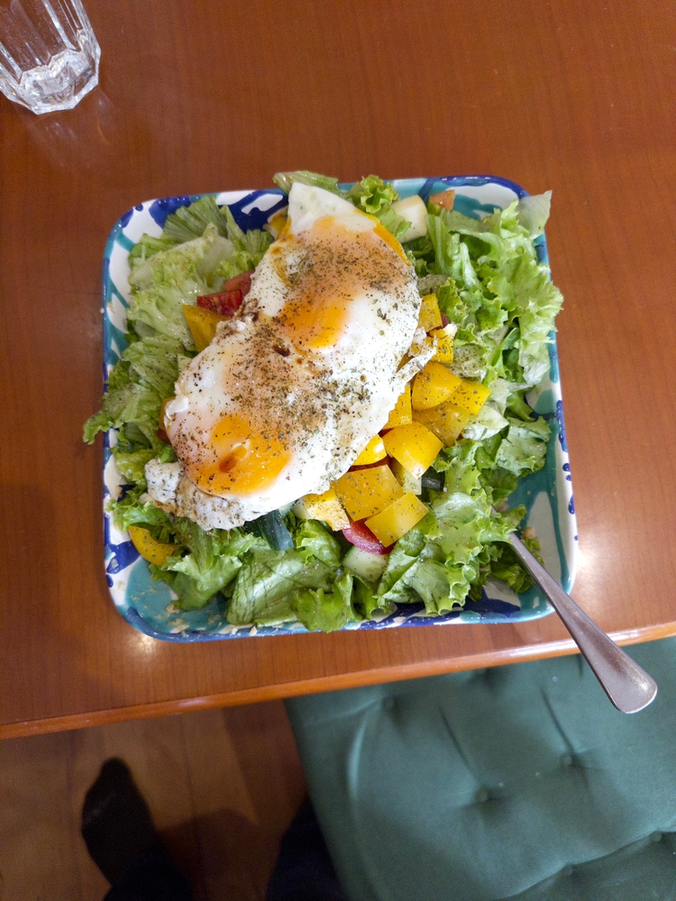 A salad with eggs, lettuce, hummus, and other vegetables
